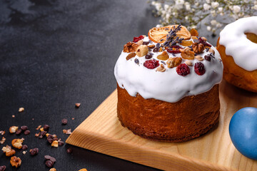 Festive cakes with white glaze, nuts and raisins with Easter eggs on the festive table