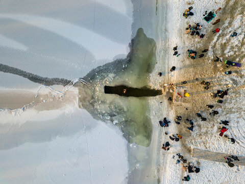 Aerial drone view. Epiphany swimming in an ice-hole in the river. Sunny frosty winter morning.