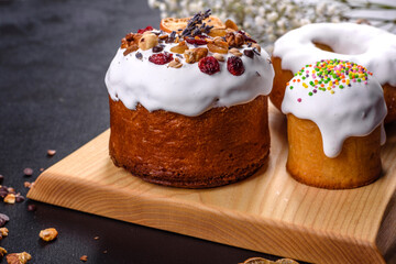 Festive cakes with white glaze, nuts and raisins with Easter eggs on the festive table