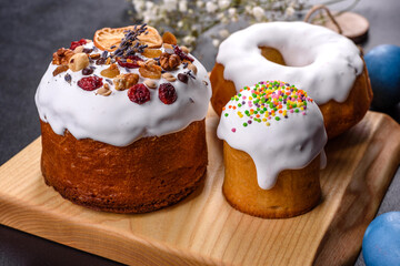 Festive cakes with white glaze, nuts and raisins with Easter eggs on the festive table