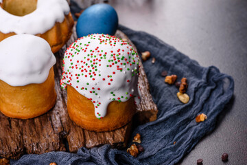 Festive cakes with white glaze, nuts and raisins with Easter eggs on the festive table