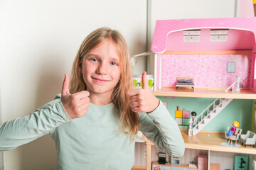 Happy girl plays with doll house and dolls. Happy child.