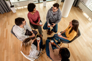 Diverse group of people sitting in circle in group therapy session. - obrazy, fototapety, plakaty