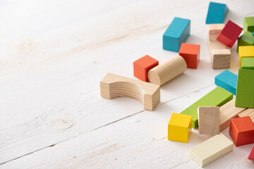 Colorful wooden toy blocks on white wooden table background. Natural materials. Healthy childhood....