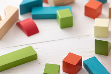 Closeup of colorful wooden toy blocks on white background wooden table. The child plays with colored cubes.