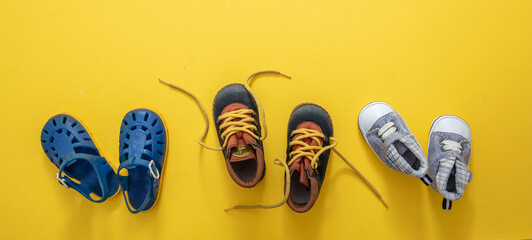 Baby boy blue shoes variety on yellow color background, top view..