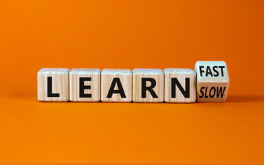 Learn slow or fast symbol. Turned wooden cubes and changed words 'learn slow' to 'learn fast'. Beautiful orange background, copy space. Business and learn slow or fast concept.