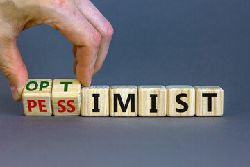 Pessimist or optimist symbol. Businessman turns cubes and changes the word 'pessimist' to...
