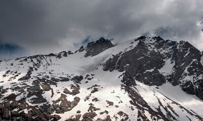 Fototapeta na wymiar Snowy peak in the mountains under the clouds.