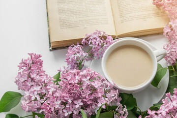 spring cozy composition flat lay coffee cup, book, lilac branches, spring season concept