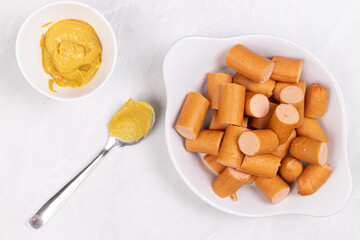 Sliced Cooked Hot Dogs served on the plate with Mustard