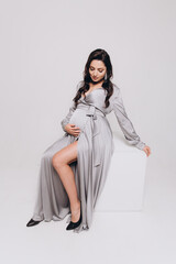 Pregnancy photoshoot of a beautiful couple, future parents in a gray dress and suit