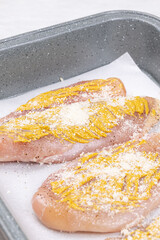 Raw chicken breasts with mustard and cheese ready for baking