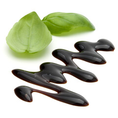 Obraz premium Balsamic vinegar cream and basil leaves isolated on white background. Italian salad dressing, sauce.