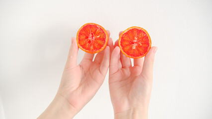 Slice of red blood orange in hands on a wooden table background