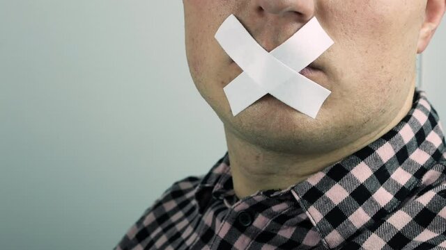A person's mouth is closed with adhesive tape, lips are sealed with sticky tape, a plaster on the lips