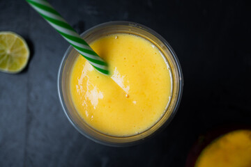 A shot looking down onto a fresh fruit juice or smoothie drink with reuseable gren and white striped straw. Flat lay style image of fresh healthy fruit juice includes fresh fruit