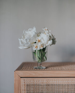 Weiße Frühlingsblumen in einr Glasvase auf einem Schrank
