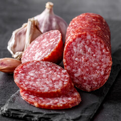 Traditional smoked salami sausage with spices.Salami sausage slices on a black chopping Board. Dark...