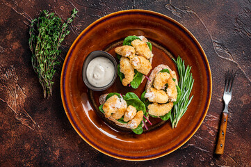 Fototapeta na wymiar Sandwichs with Fried Shrimps, Prawns, spinach and chard salad on a rustic plate. Dark background. Top view
