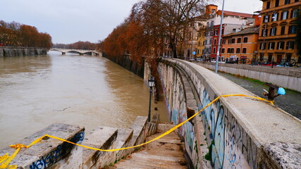 Fototapeta na wymiar Rome, Italy: Tiber river high tide water rise with no cross yellow tape line. High water level flooding the banks of the river crossing the Italian capital, after heavy rain.