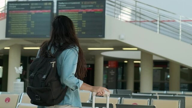 Young woman standing in lobby of the railway station with luggage