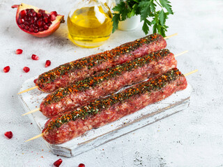 raw beef lamb lula kebab on wooden skewer on a board, close up