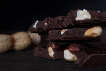 Chocolate bar with peanuts isolated on dark background with walnut. 