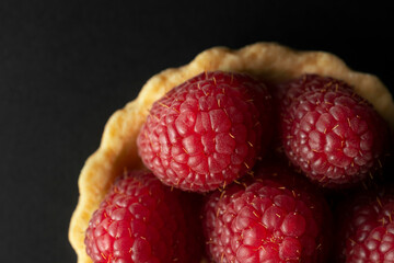 Raspberry tart, top view macro photography. Homemade raspberry tart on the black background.