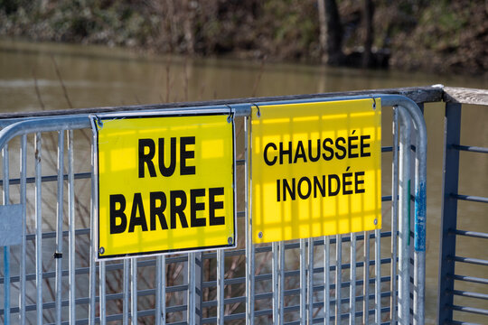 M&eacute;t&eacute;o - Alertes inondations. Panneaux d'avertissement &eacute;crits en Fran&ccedil;ais : "Rue barr&eacute;e" et "Chauss&eacute;e inond&eacute;e" fix&eacute;s sur des barri&egrave;res m&eacute;talliques