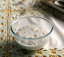 Transparent, glass bowl with sourdough for yeast dough, bakery products. Ready to knead the dough, sourdough. Home-made baking. Healthy eating-conceptual.