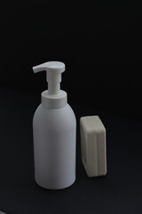 White bottle isolated on black background. Unbrending bottle for mockup. Dishwashing liquid is flowing from bottle.