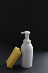 White dispenser bottle with dish washing liquid and yellow sponge. Copy space. Mockup, minimalistic style/