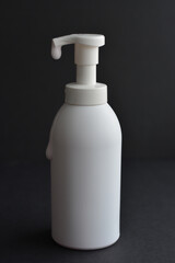 White bottle isolated on black background. Unbrending bottle for mockup. Dishwashing liquid is flowing from bottle.