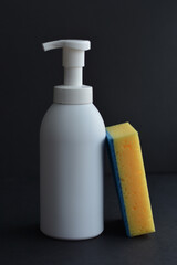 Fototapeta na wymiar White dispenser bottle whith dish washing liguid and yellow sponge. Copy space. Mockup, minimalistic style.