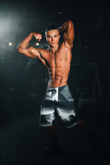 Young sports athlete guy shows muscles in the gym, doing sports, healthy lifestyle.