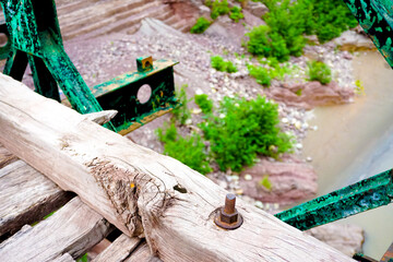 Photo focussed on old rustic screw nut and weathered old wood with knots on a broken bridge with bokeh background.