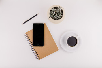 workplace on white background with notepad smartphone flower and pen and cup of coffee