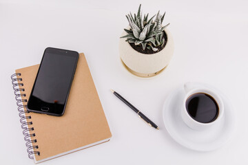workplace on white background with notepad smartphone flower and pen and cup of coffee