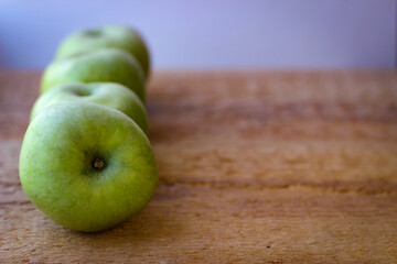 Green apples stand on a wooden surface