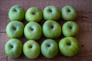 Green apples stand on a wooden surface