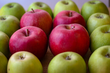Green and red apples stand on a wooden surface