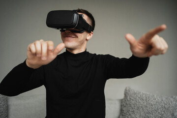 Naklejka premium VR gamer is playing a virtual reality game at home. favorite hobby. a man in a jacket is studying a new profession. the programmer puts a helmet on his head in black for.