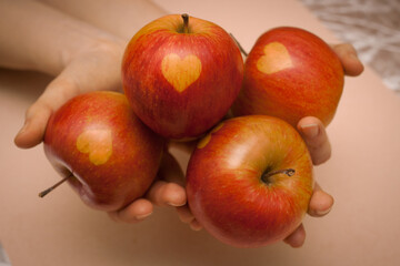 Person holding tasty delicious red and green apples in hand. Apples have a heart on them, good as a valentines present or concept of healthy food.