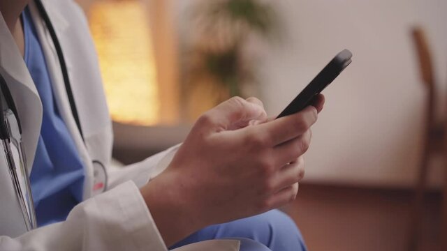 Hands of professional female doctor consulting patient remotely in online chat from her smart phone. Healthcare professional consulting her phone.