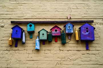 Multicolored art birdhouses composition on the brick wall. Curious installation of wooden bird nests on the house. Selective focus.