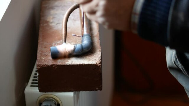 Close-up of autogenous welding of copper pipe, urgent repair welding of malfunctional home central heating system