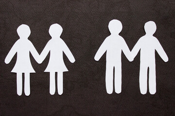 Two same-sex couples of people holding hands cutting from white paper on black background. A couple of women and a couple of men. Concept of same sex love, relationship, gender identity 