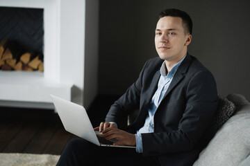 a financier of Caucasian appearance works typing a text message on a laptop computer. social network chat with partners. The financier is a man in a business suit sitting in a modern office.