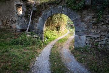 Fototapeta na wymiar a gravel road passing under a stone arch in Las Herrerias hamlet (Vega de Valcarce), El Bierzo, province of Leon, Castille and Leon, Spain